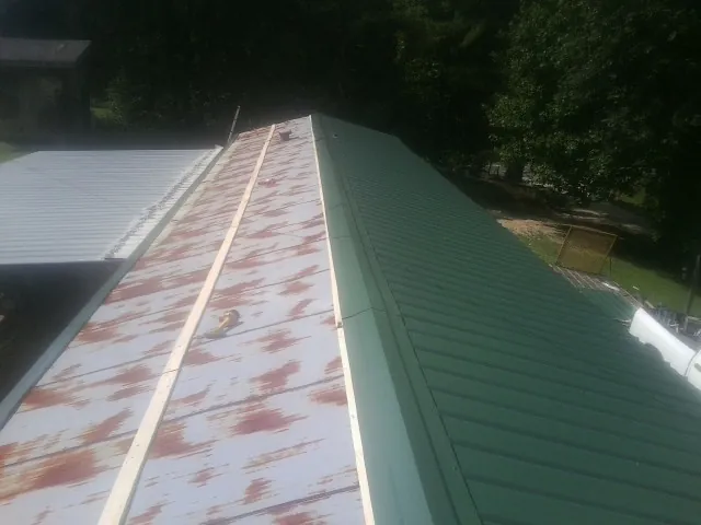Old rusted panels beside newly installed green metal roofing — Wind Damage Roof Repair by Roofing Brothers in Venetia