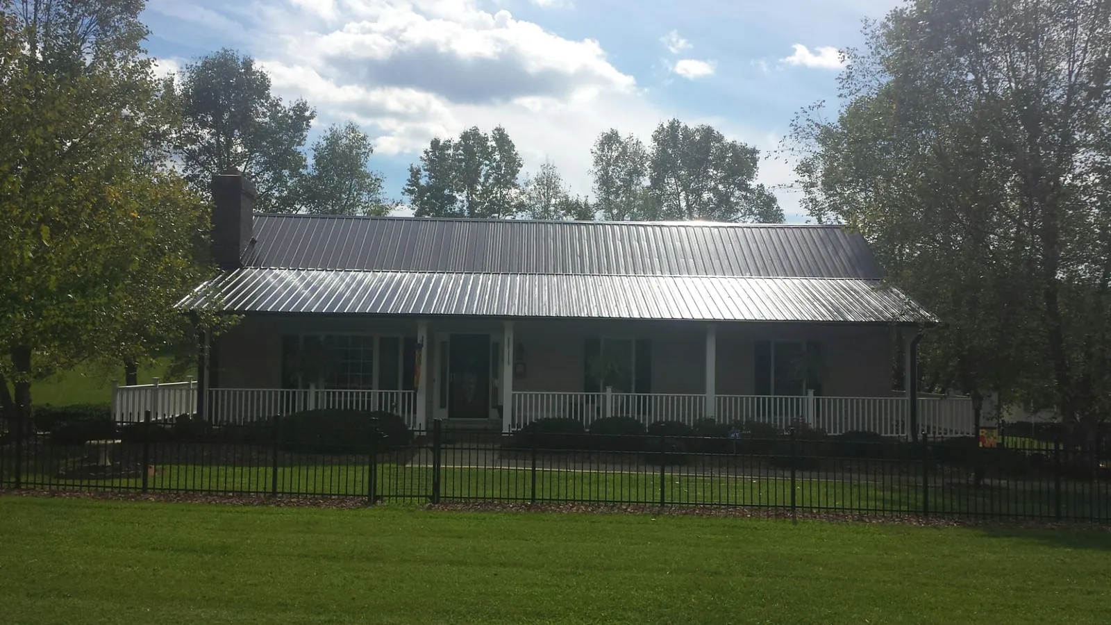 Gray metal roof on a brick ranch with a full width front porch — Gutter Guard Installation work by our crew in Venetia