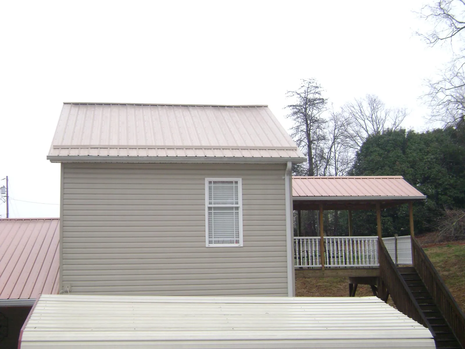 Tan metal roofs on a two story addition and attached porch, from a Roof Replacement job in Venetia