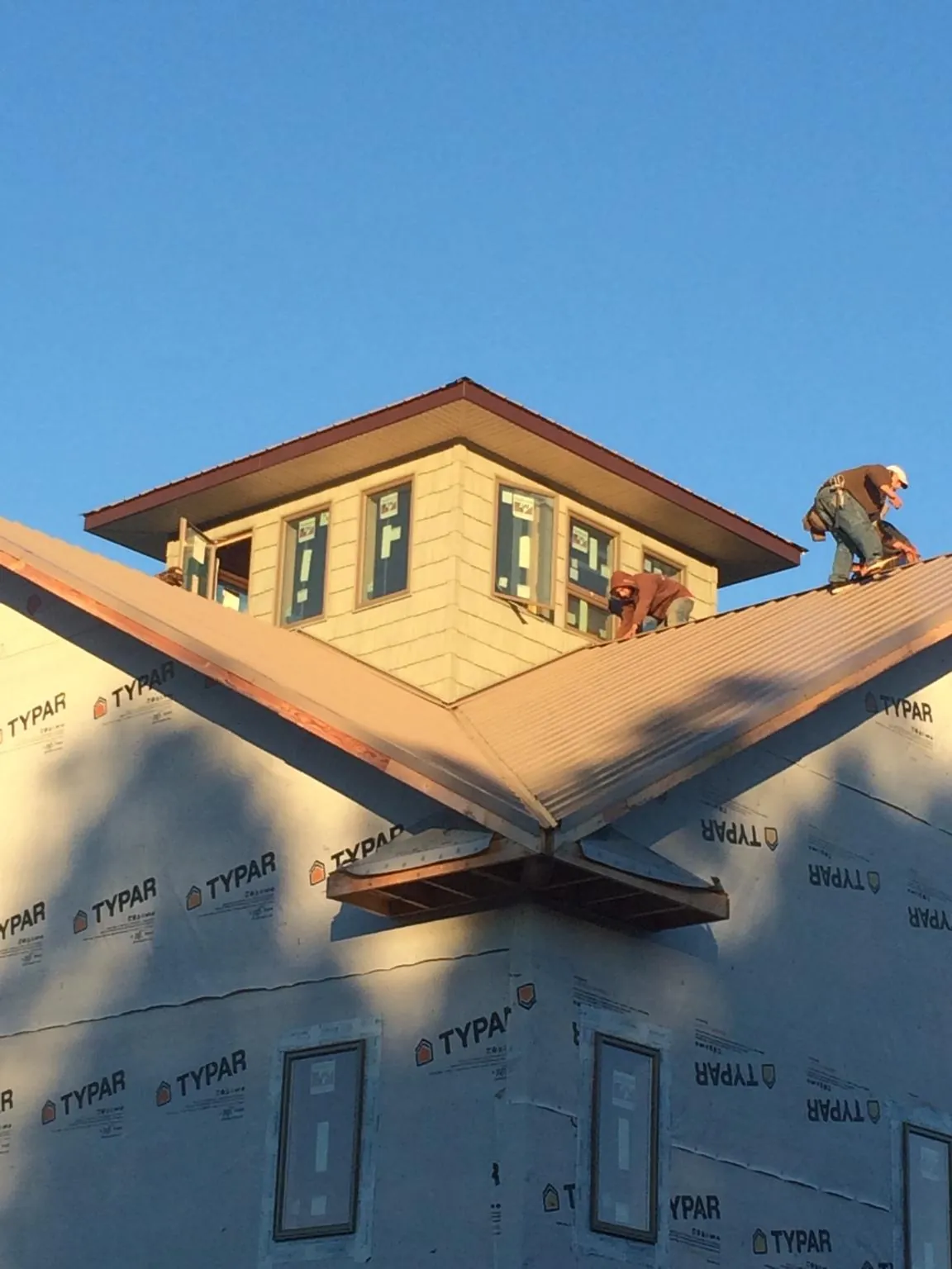 Roofers working around a rooftop cupola on a new metal roof at sunset — Roof Waterproofing in Venetia by Roofing Brothers